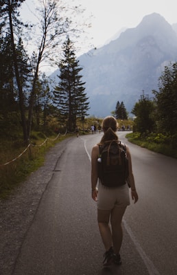 a woman with a backpack walking down a road