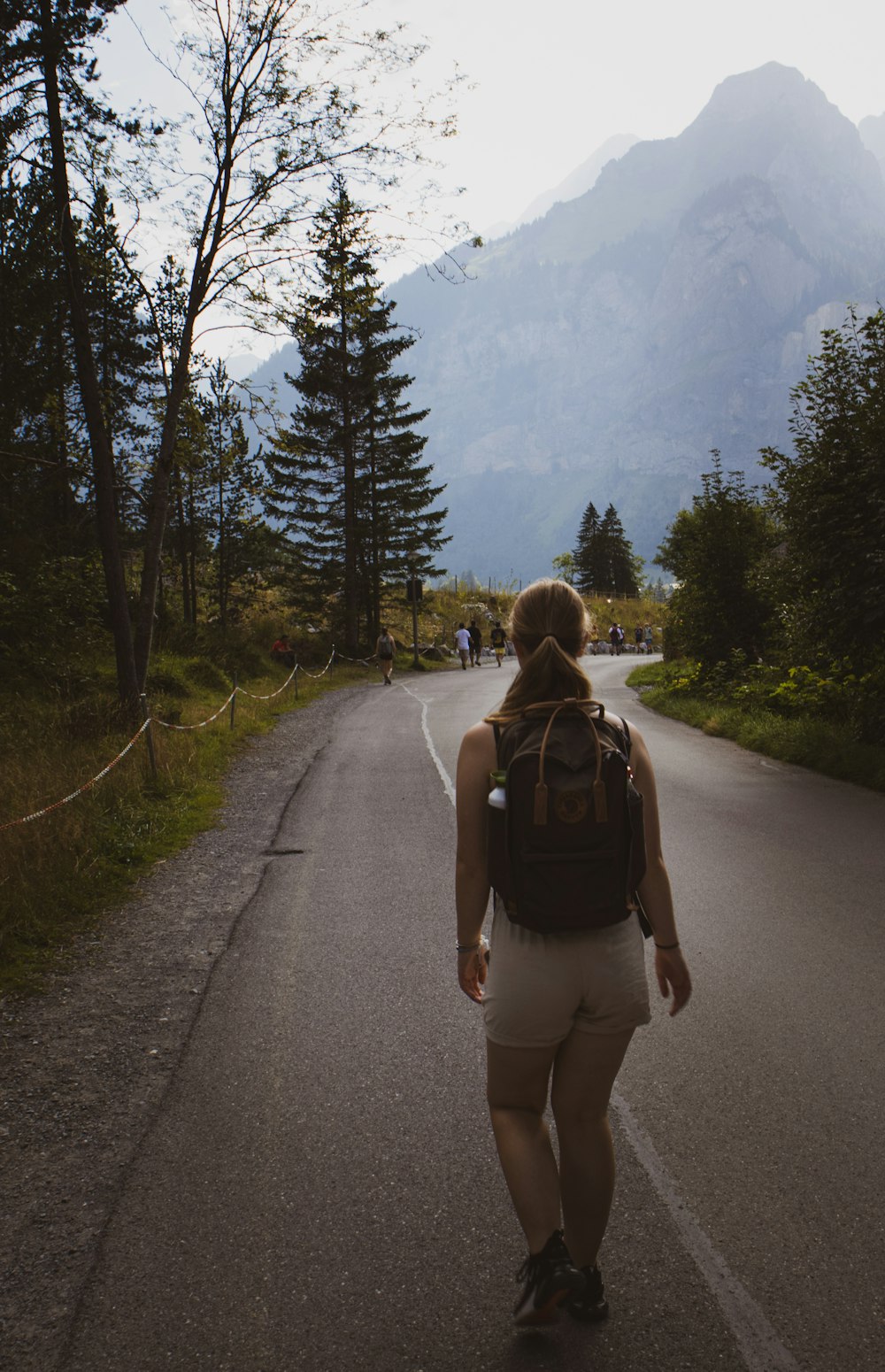 a woman with a backpack walking down a road