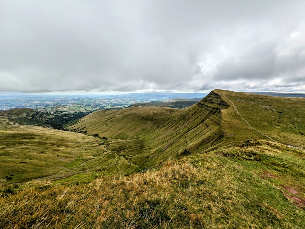 a view of a grassy hill with a cloudy sky