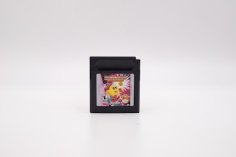 A black cartridge with a colorful label featuring a yellow character and bright design elements, set against a plain white background.