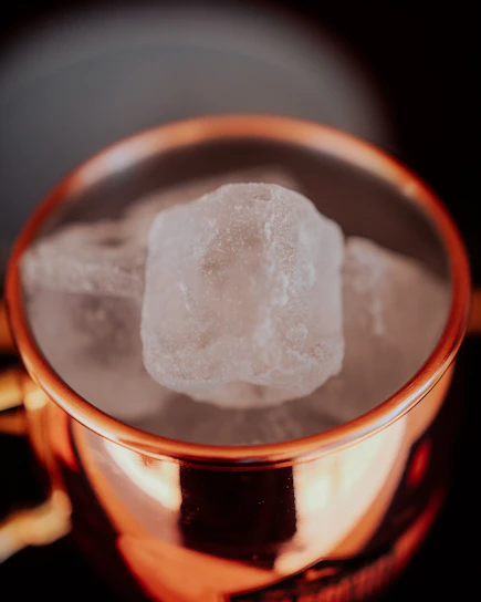 A close-up of a hammered pure copper water bottle glowing softly under warm light, highlighting its handcrafted texture.