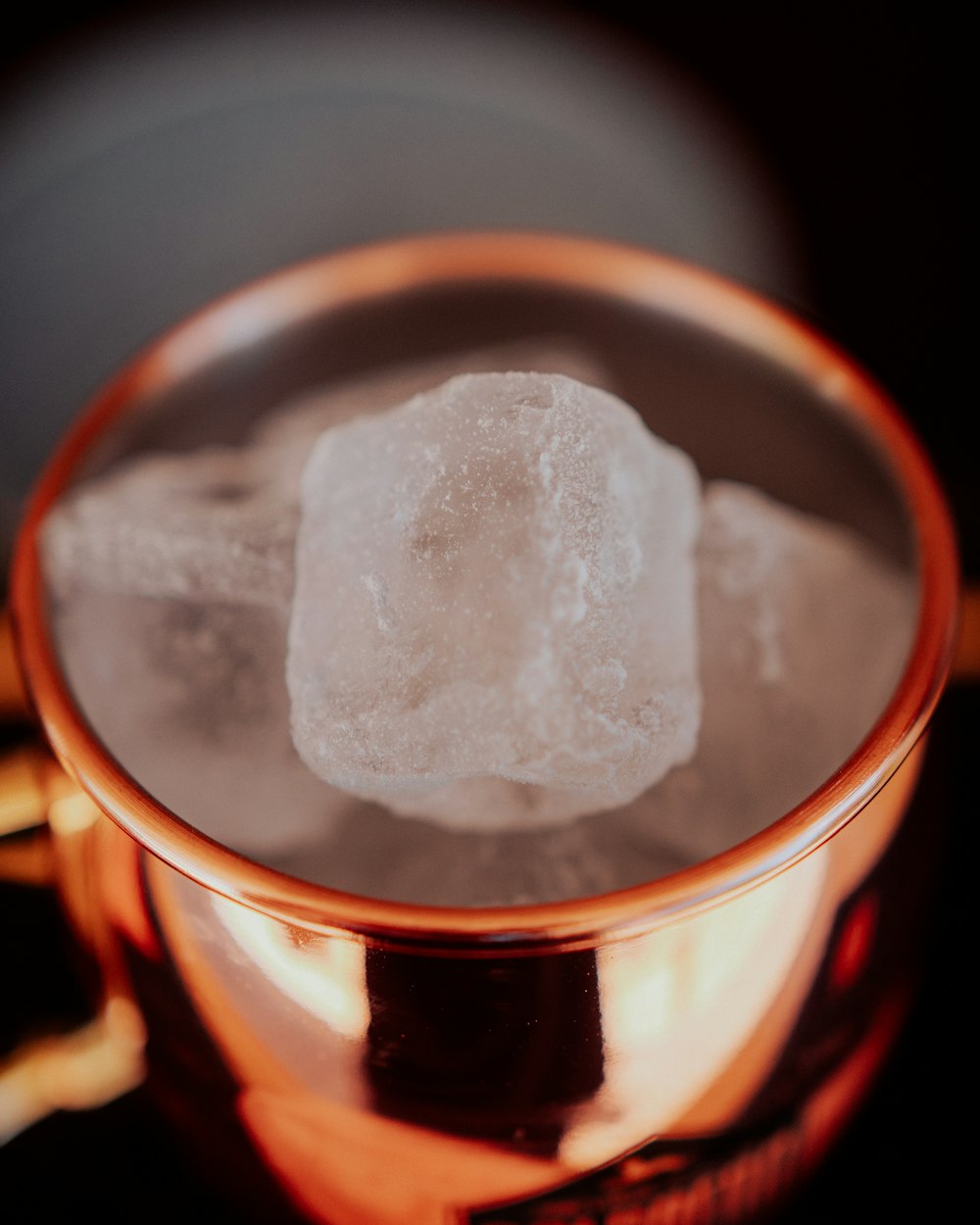 a copper mug filled with ice cubes on top of a table