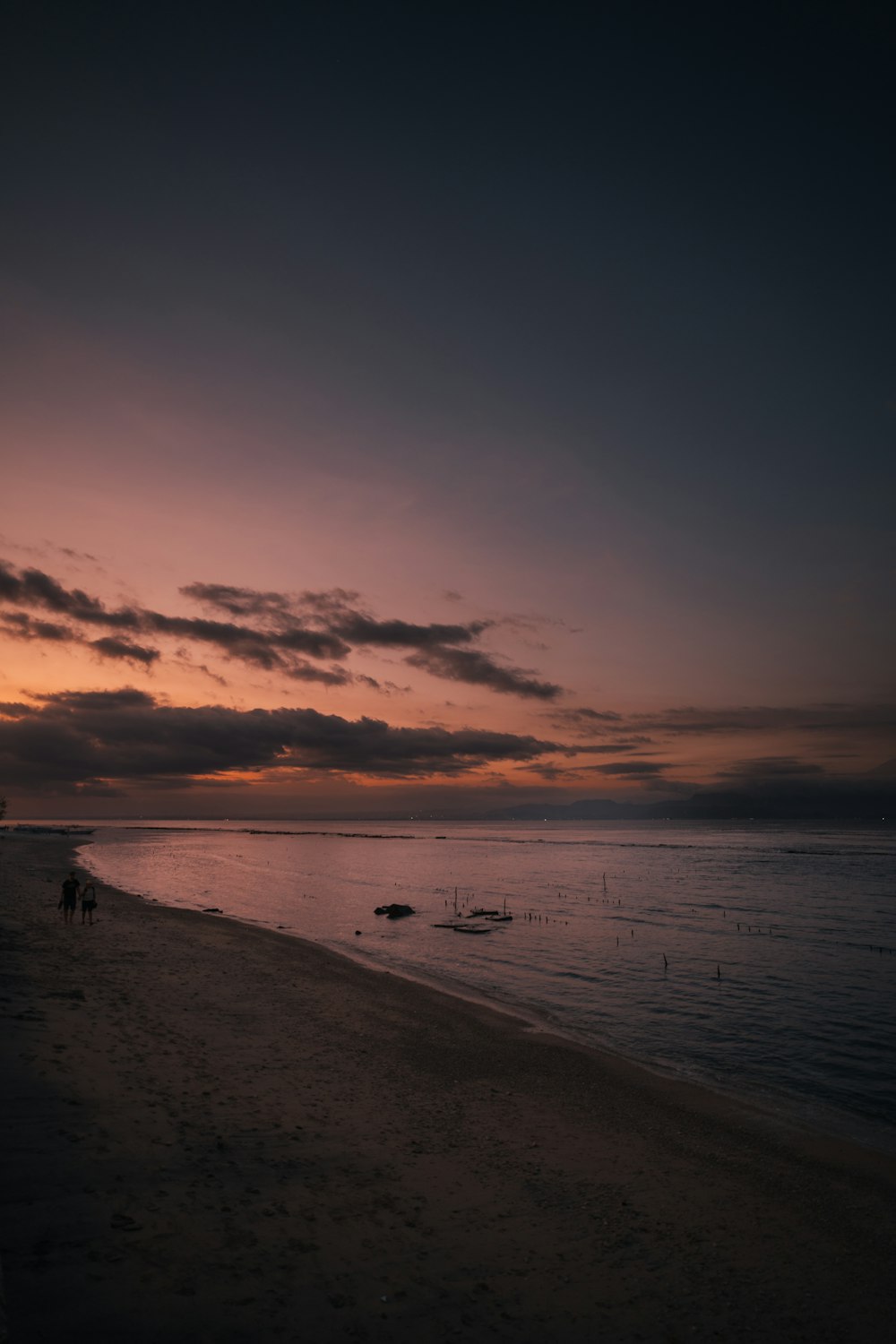 a sunset on a beach with boats in the water