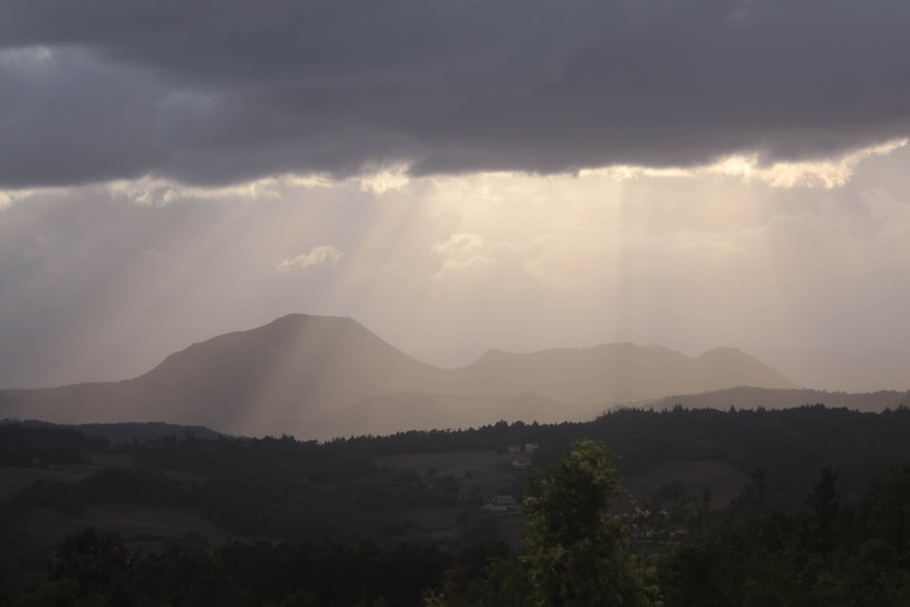 the sun is shining through the clouds over the mountains