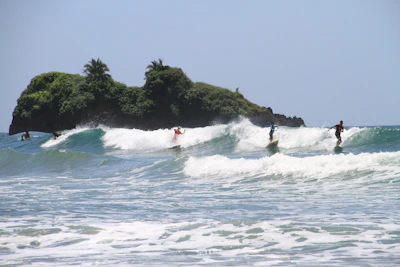 A vibrant photo of tourists enjoying a surf lesson at Eko Mangsit Lombok with clear blue waves.