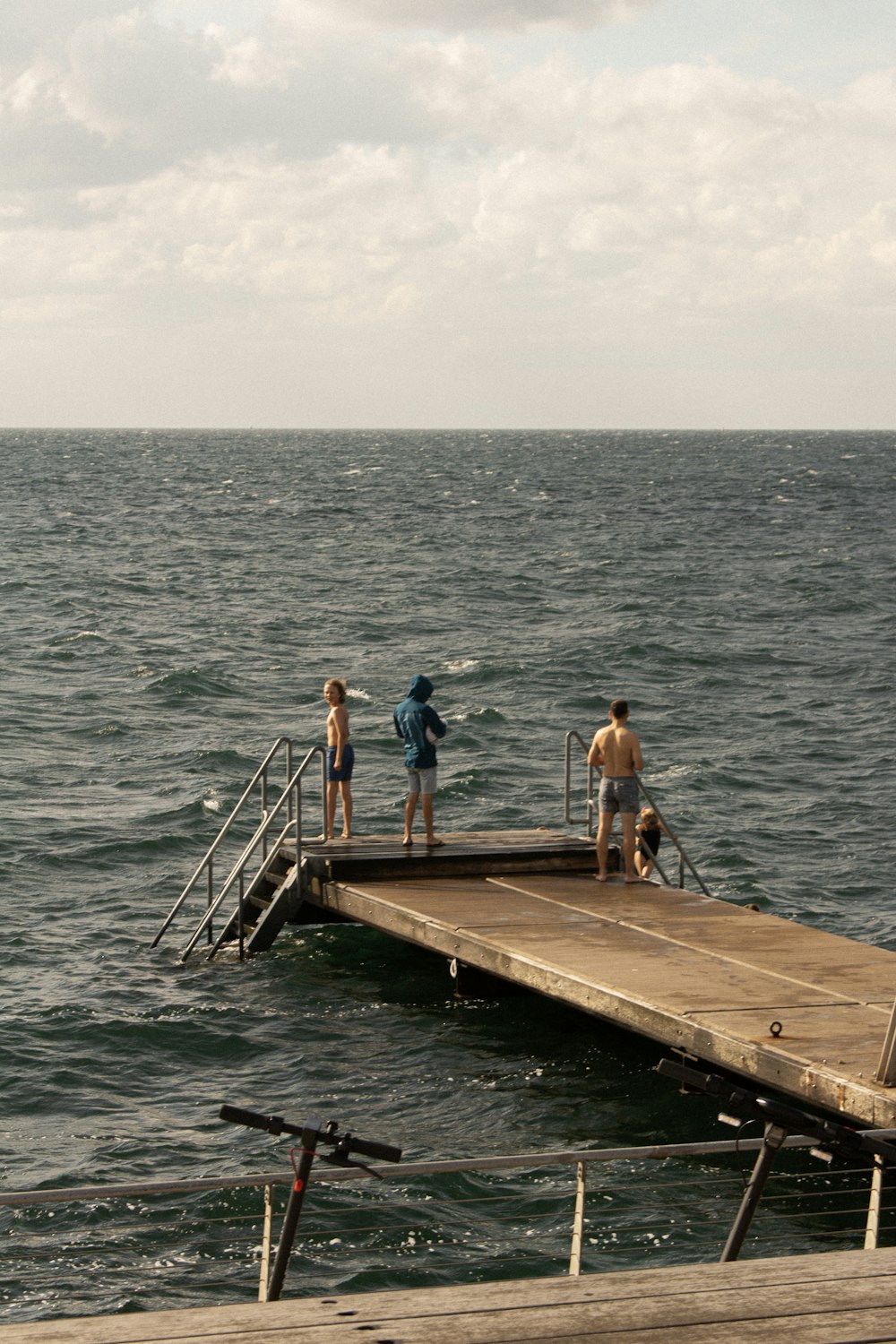a group of people standing on a dock next to the ocean