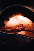 Close-up of a sizzling wood-fired pizza fresh out of the oven with bubbling cheese.