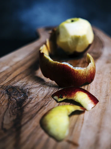 A close-up of a sharp peeler on a rustic wooden surface with gentle sunlight.