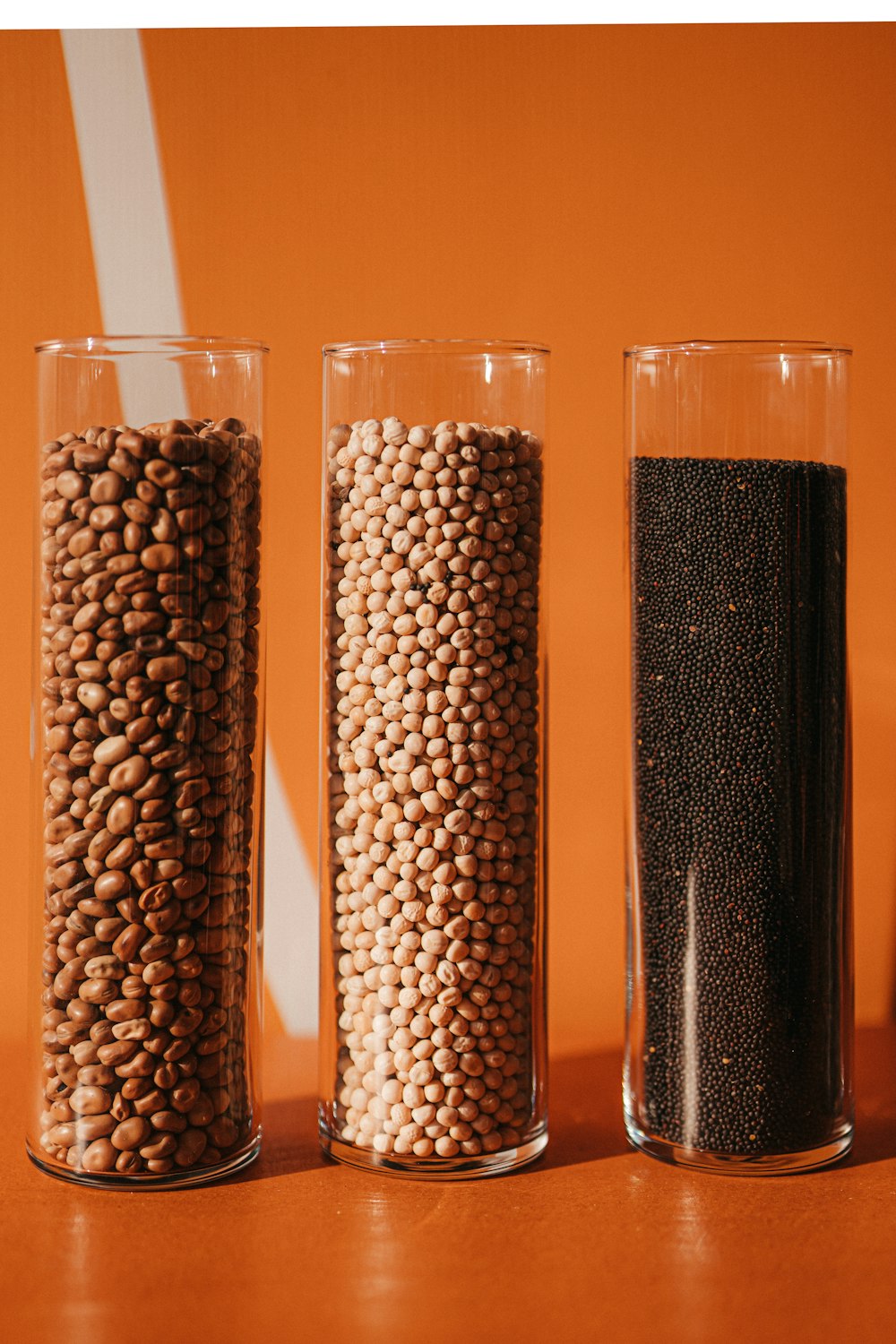 a row of three glass vases filled with grains