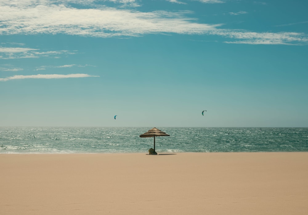 a beach with a umbrella and a person sitting under it