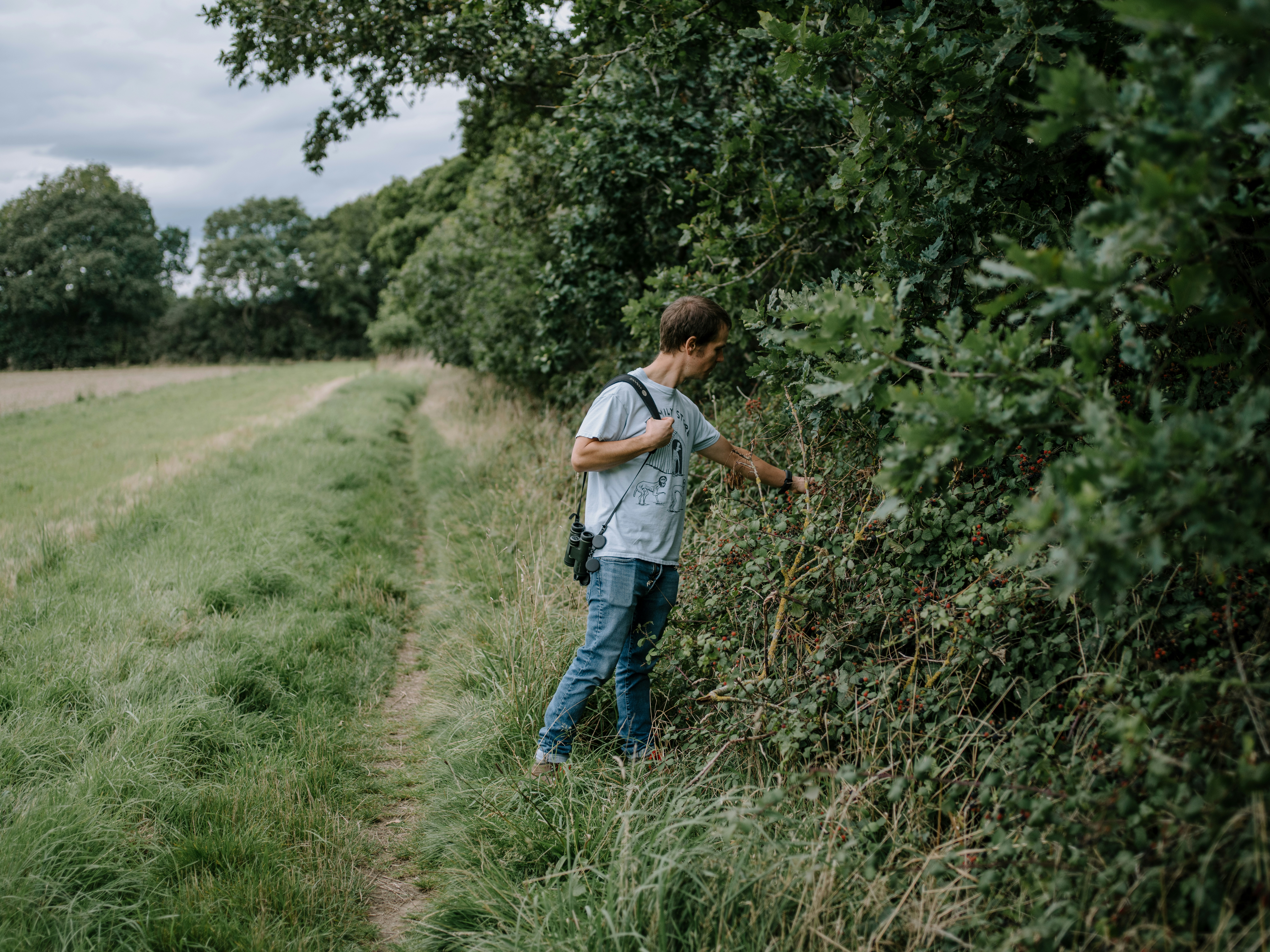 a man standing next to a lush green field