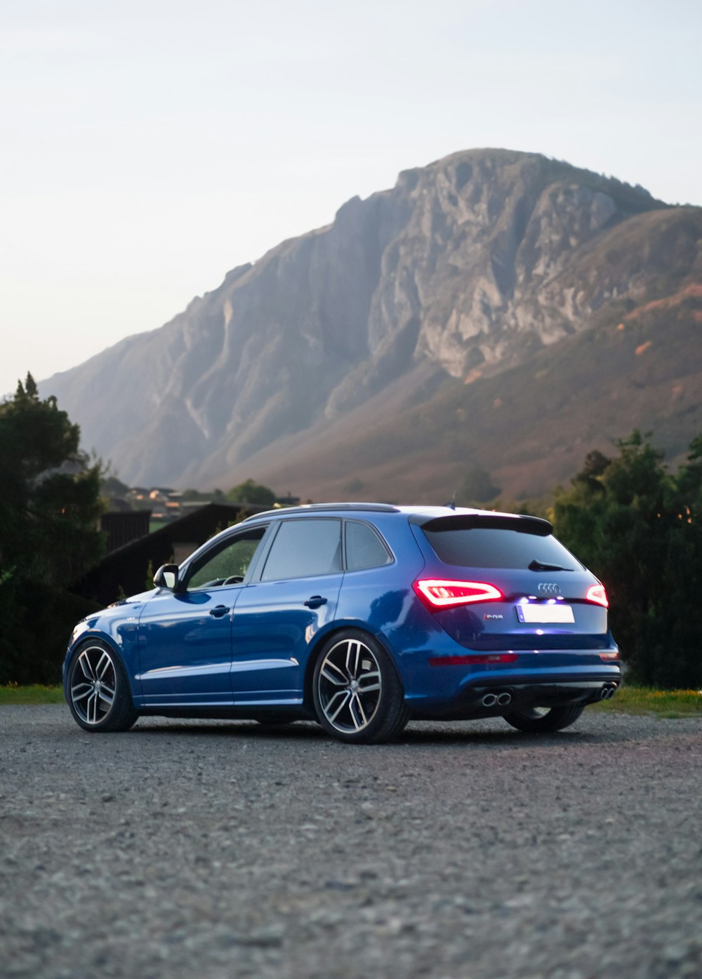 a blue car parked in front of a mountain