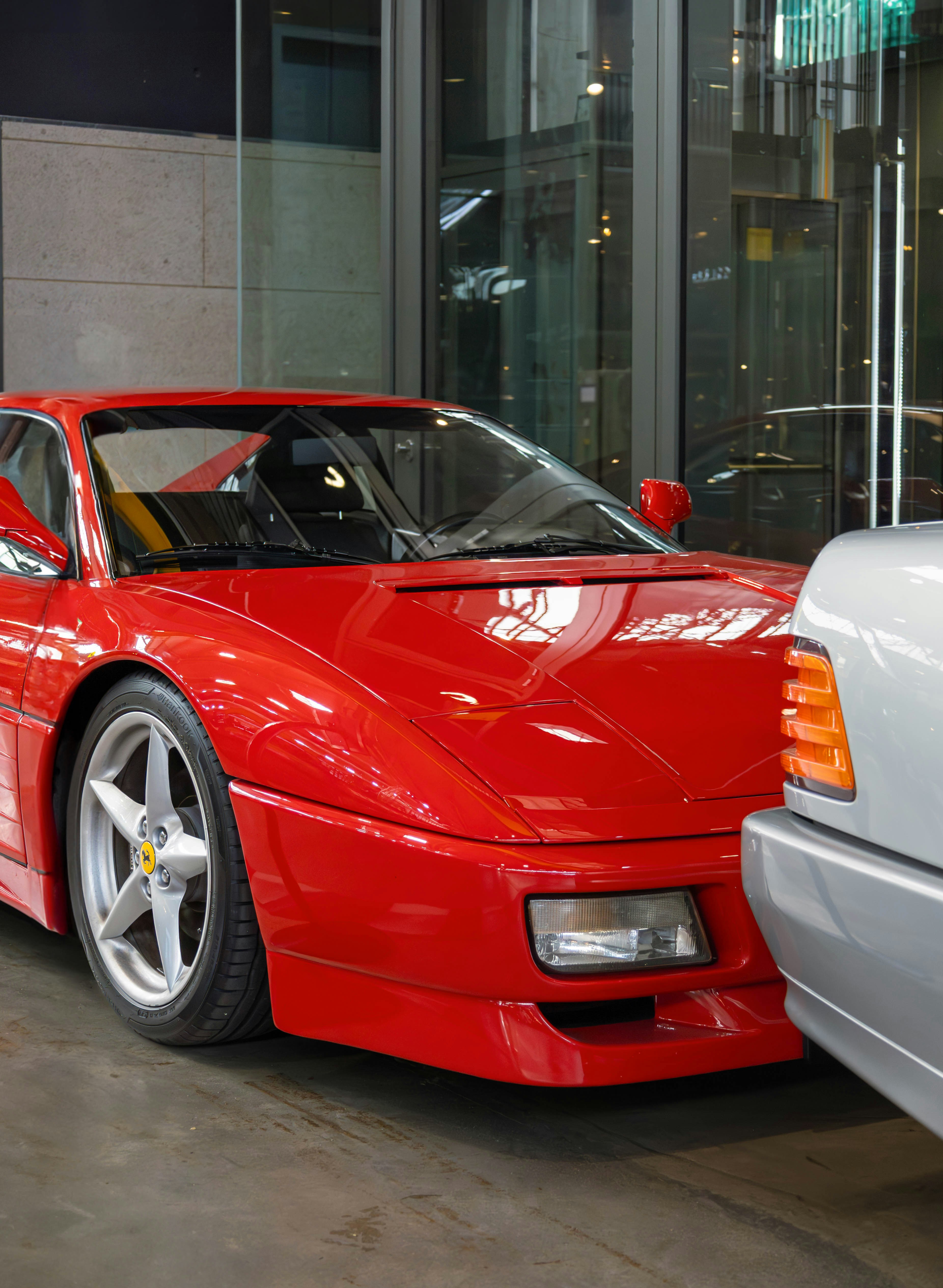 a red sports car parked next to a white car