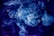 Swirling clouds of smoke create an intricate and ethereal pattern against a dark background. The smoke is primarily in shades of blue and white, forming wispy, translucent shapes that seem to dance through the air.
