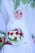 A bride wearing a white hijab and intricate lace gown holds a vibrant bouquet of red and white roses. She is adorned with a sparkling tiara and surrounded by lush greenery and delicate drapery.