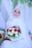 A bride wearing a white hijab and intricate lace gown holds a vibrant bouquet of red and white roses. She is adorned with a sparkling tiara and surrounded by lush greenery and delicate drapery.