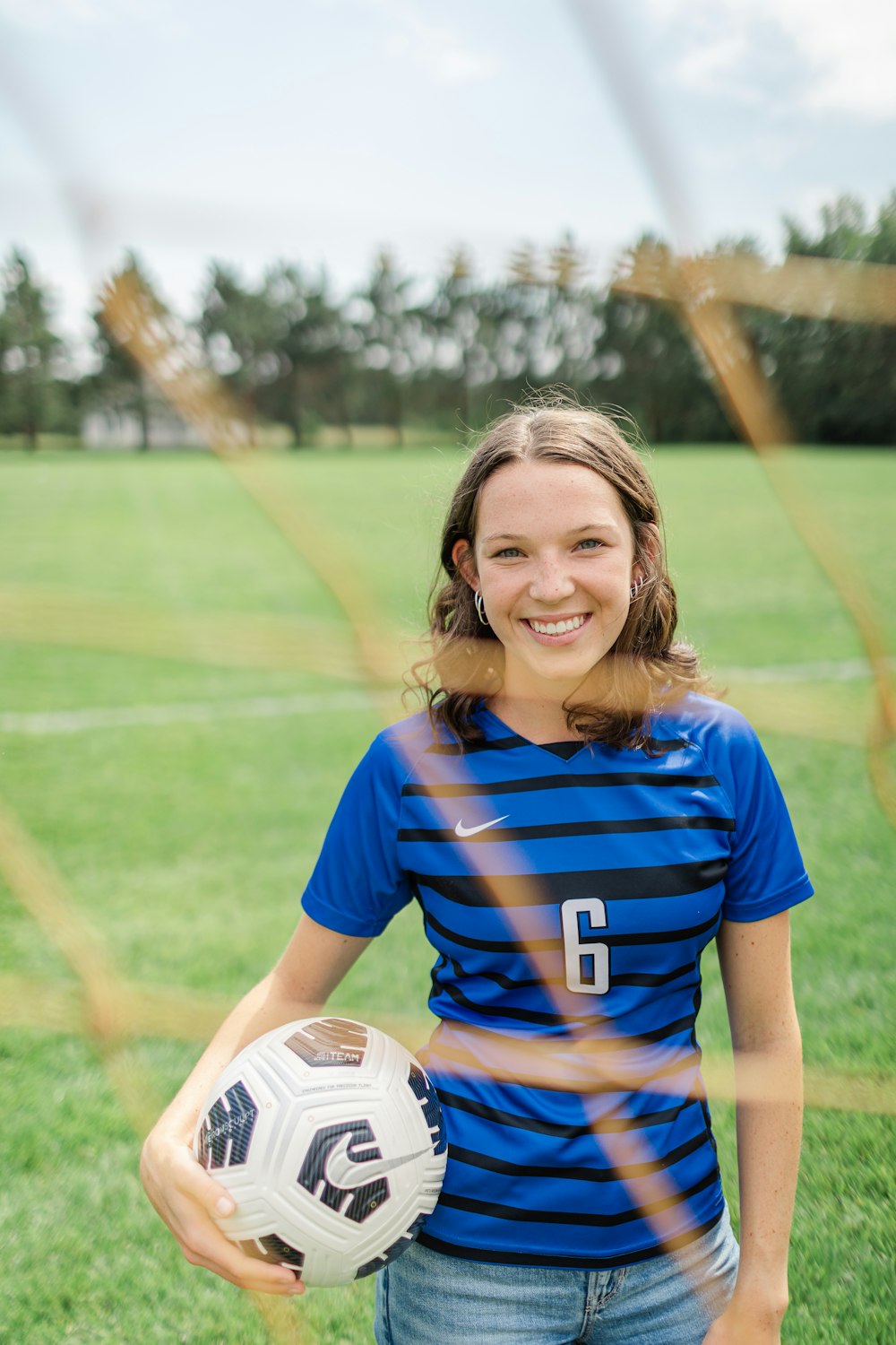a girl in a blue shirt holding a soccer ball