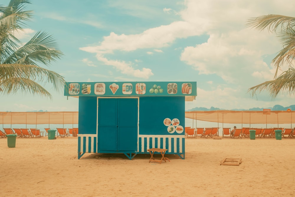 a blue and white beach hut sitting on top of a sandy beach