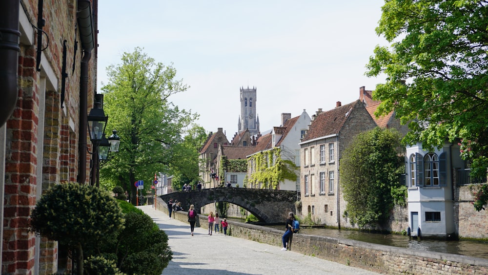 a group of people walking down a street next to a river