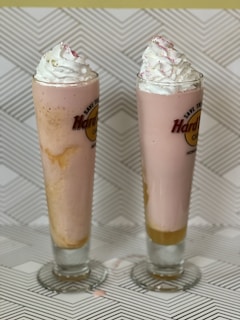 A vibrant photo of two colorful frozen yogurt shakes with a branded water bottle beside them.