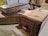 A rustic and worn index card catalog is accompanied by two old, thick books with noticeable aging and distressed covers. The background features a blurred array of books on shelves, enhancing the vintage and library-like ambiance of the scene.