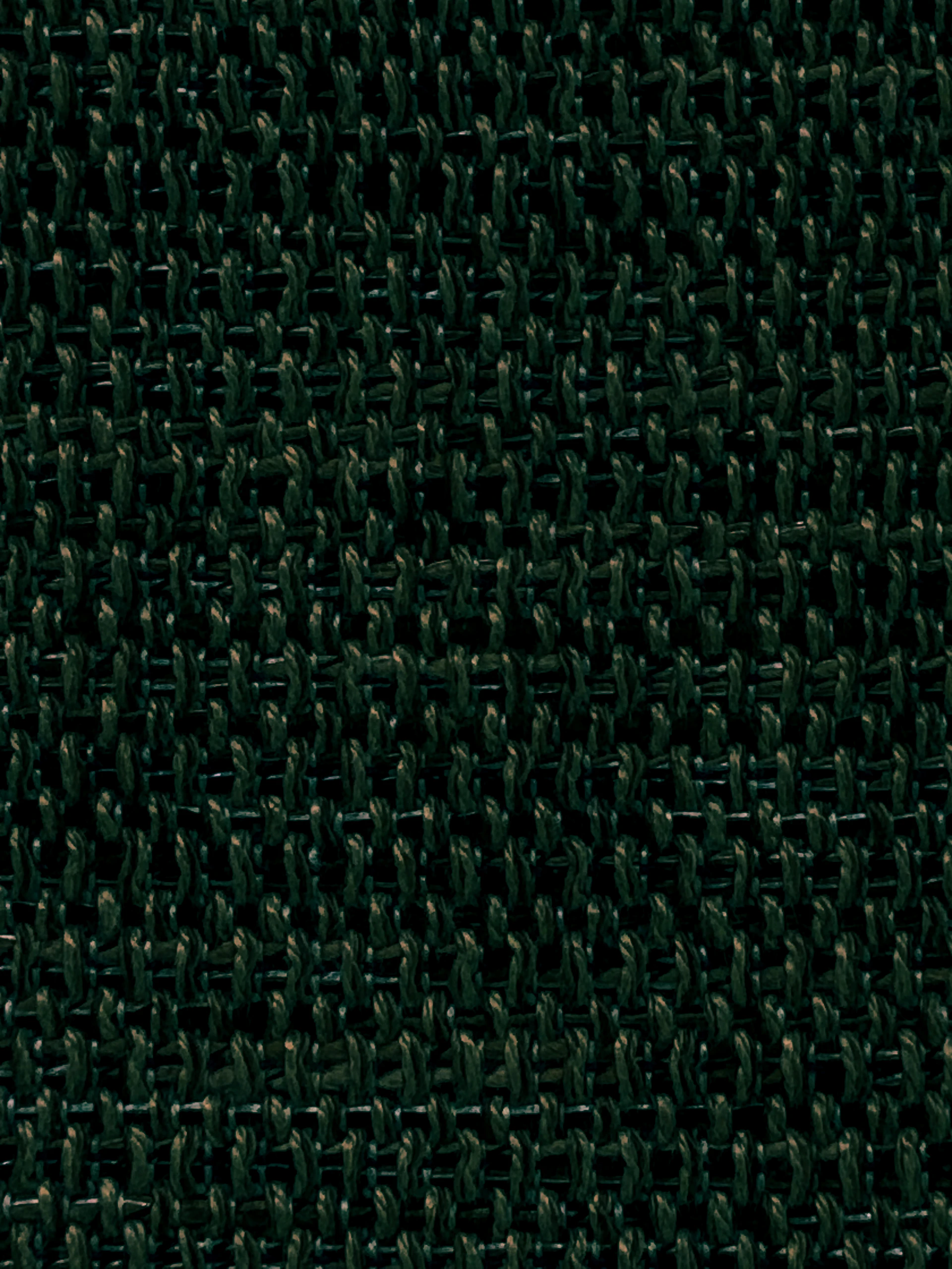 Close-up de detalhes de tecido premium em tons de verde escuro e areia, com textura que remete à natureza brasileira.