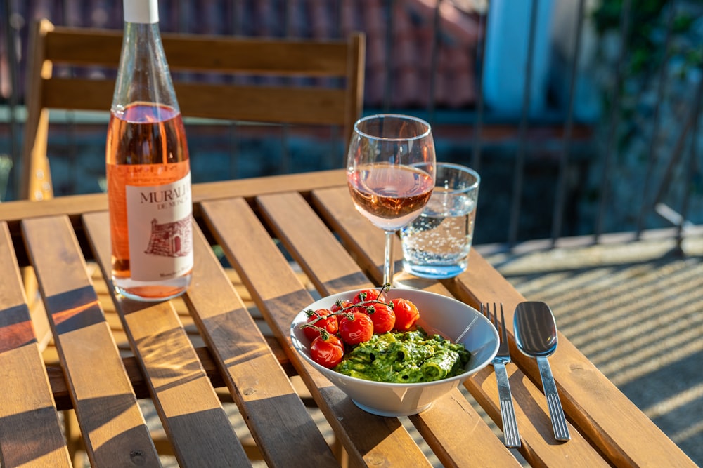 a bowl of tomatoes and a glass of wine on a table