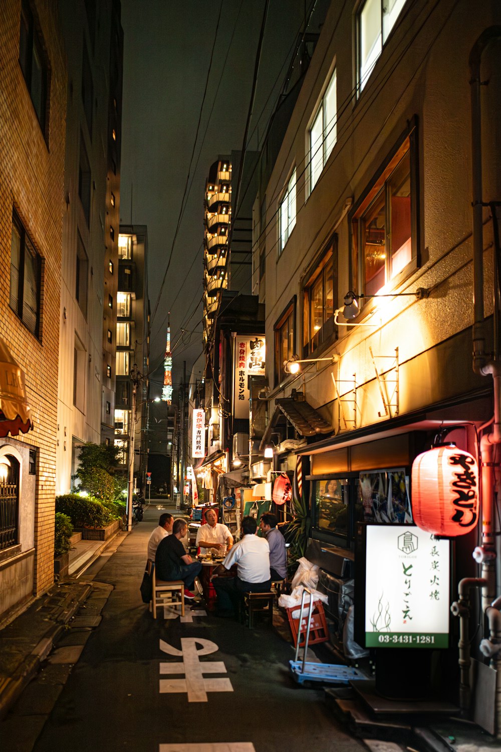 a group of people sitting at a table in an alley