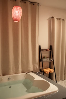 A cozy bathroom scene featuring a soft cotton towel set, a patterned shower curtain liner, and a sleek bathroom trash can.