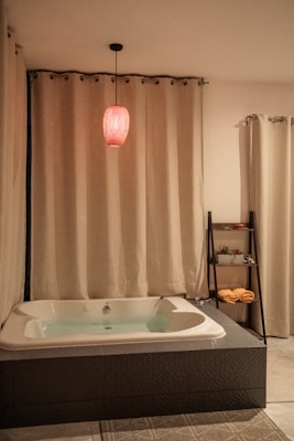 A soft, absorbent bath mat placed in front of a bathtub with gentle lighting.