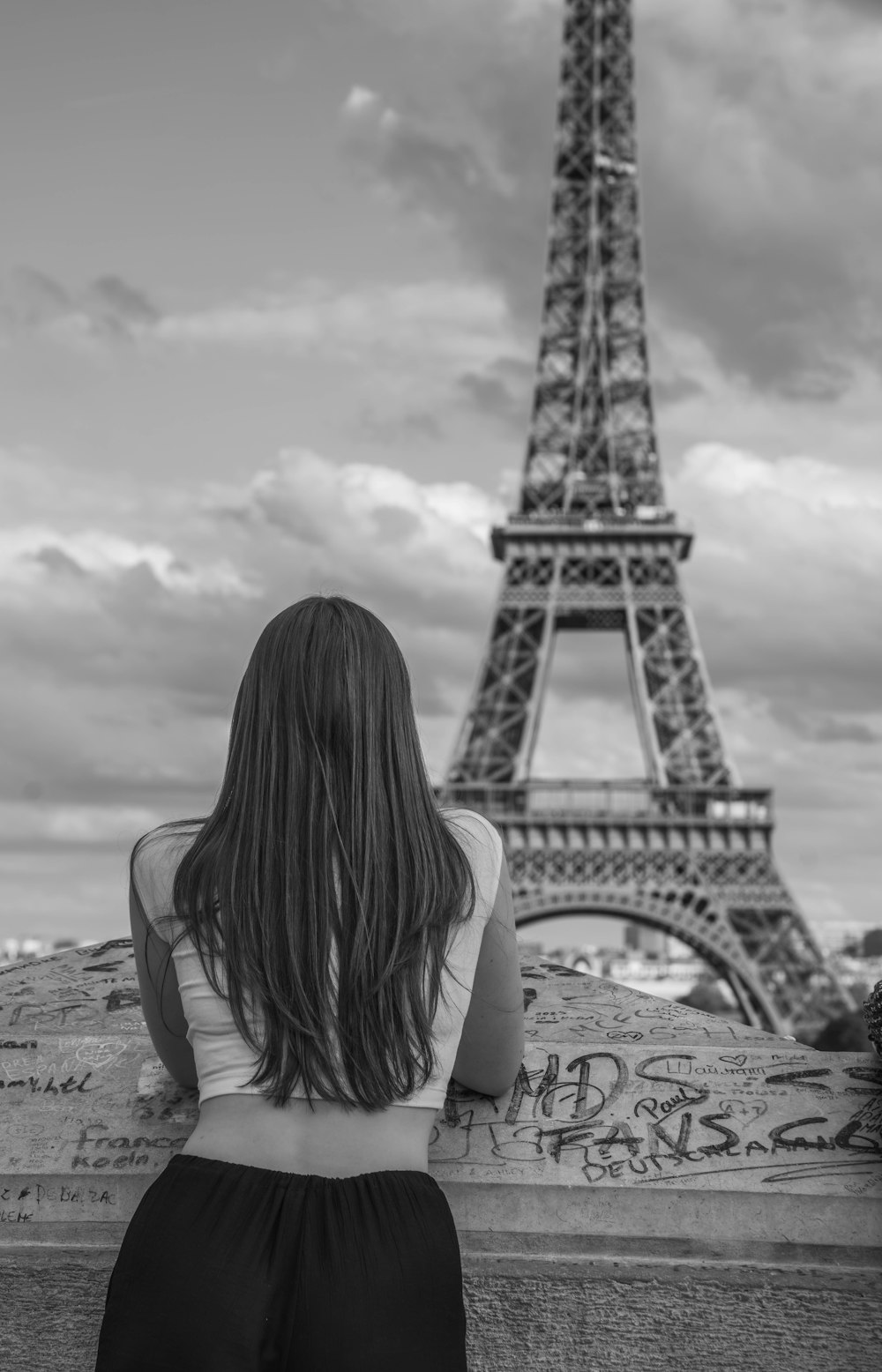 a woman sitting in front of the eiffel tower