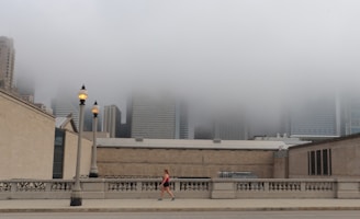 A vibrant cityscape at dawn with a woman in sleek activewear walking confidently.