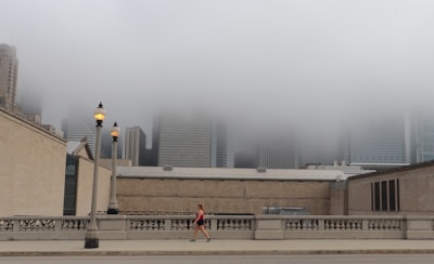 A vibrant cityscape at dawn with a woman in sleek activewear walking confidently.