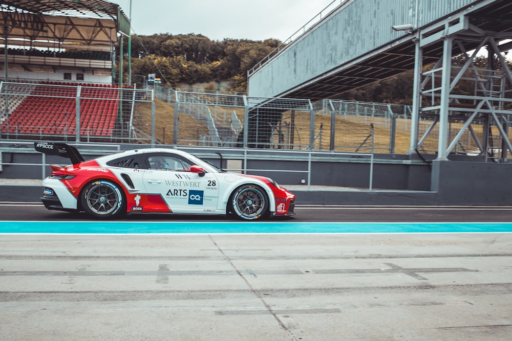 a red and white sports car driving down a race track