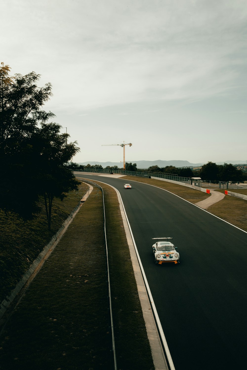 a white car driving down a road next to a forest