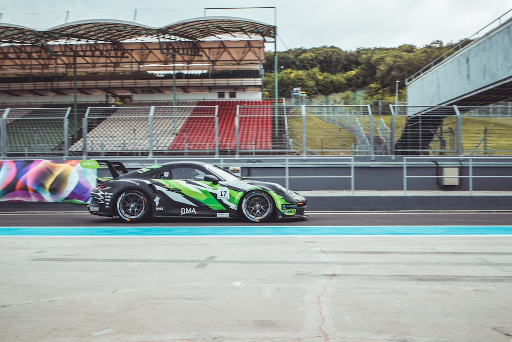 a green and black race car driving on a track