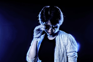 Stylish portrait of DJ Kelblizz in his signature look, gold accents glowing against a deep blue background