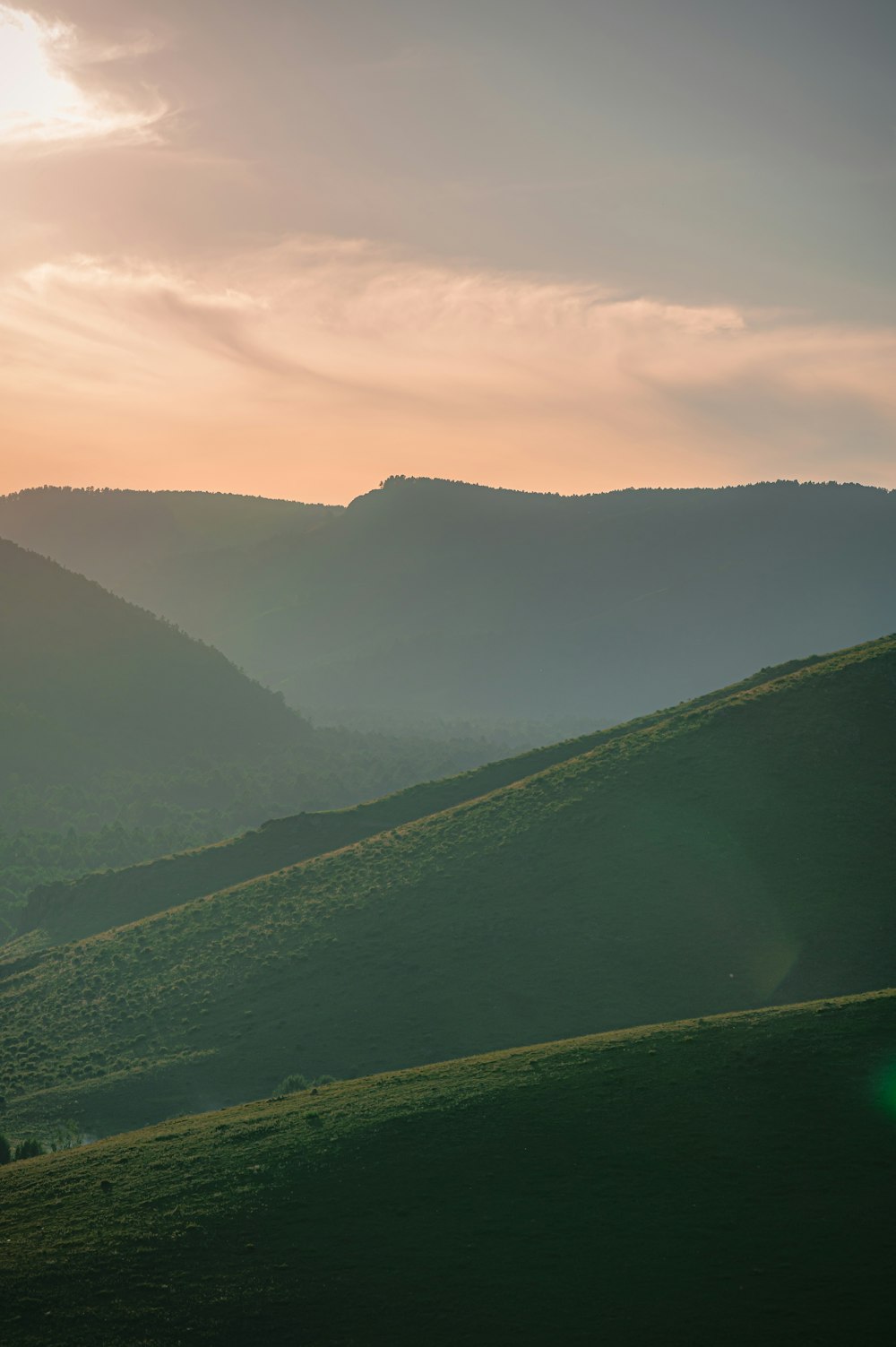 the sun is setting over the rolling hills