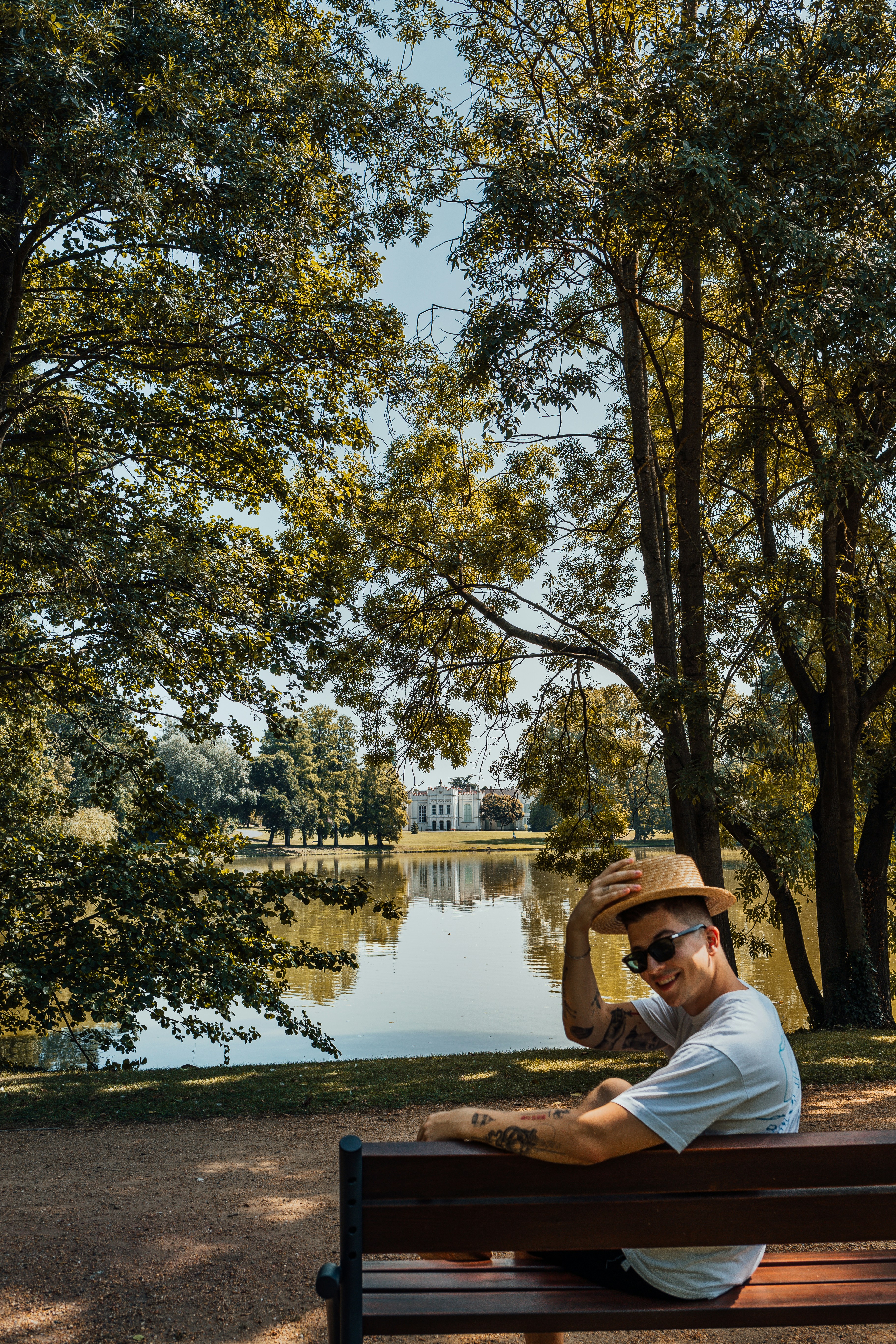 a man sitting on top of a wooden bench next to a lake