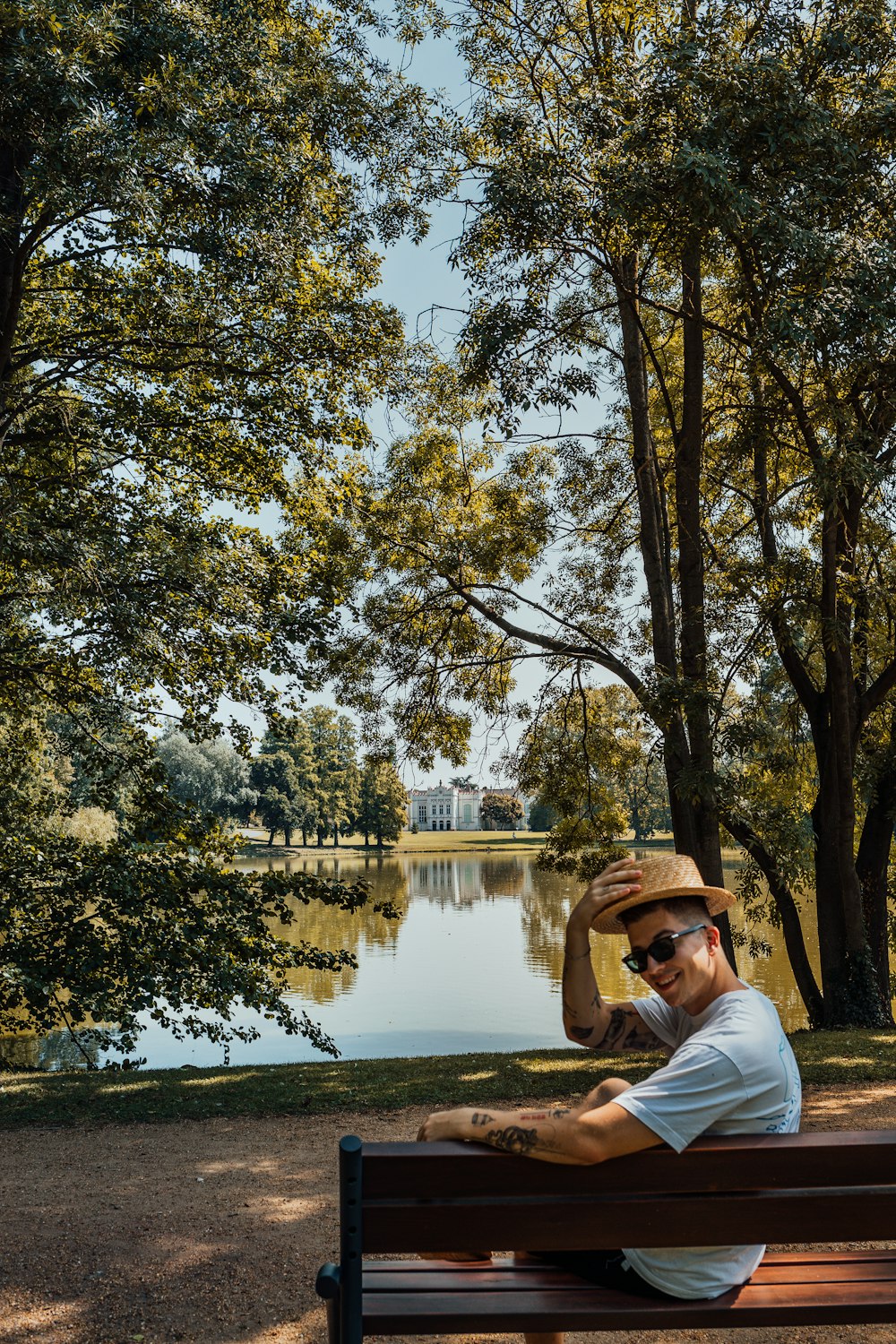 a man sitting on top of a wooden bench next to a lake