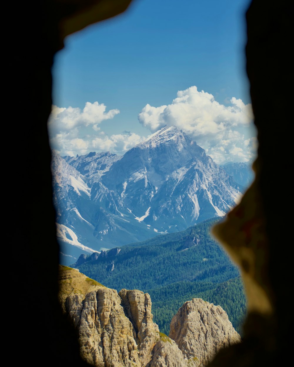 a view of a mountain range through a hole in a rock