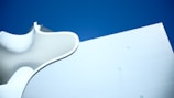 Smooth, curvy white architectural structure set against a deep blue sky, showcasing minimalist design with soft curves and geometric forms.