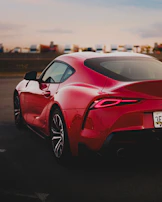 Red sports car with glossy paint reflecting the sunset on a quiet street.