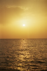 A serene sunset over a golden beach with a couple enjoying a private boat ride on calm ocean waters.