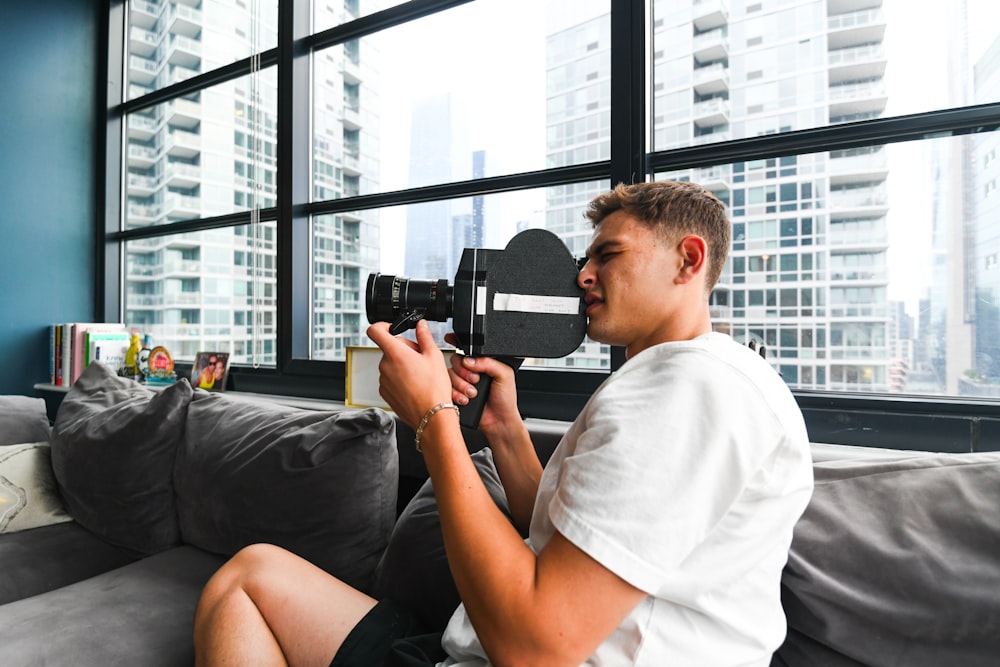 a man sitting on a couch holding a camera