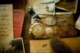 Family heirlooms including a pocket watch and faded letters on a wooden table.