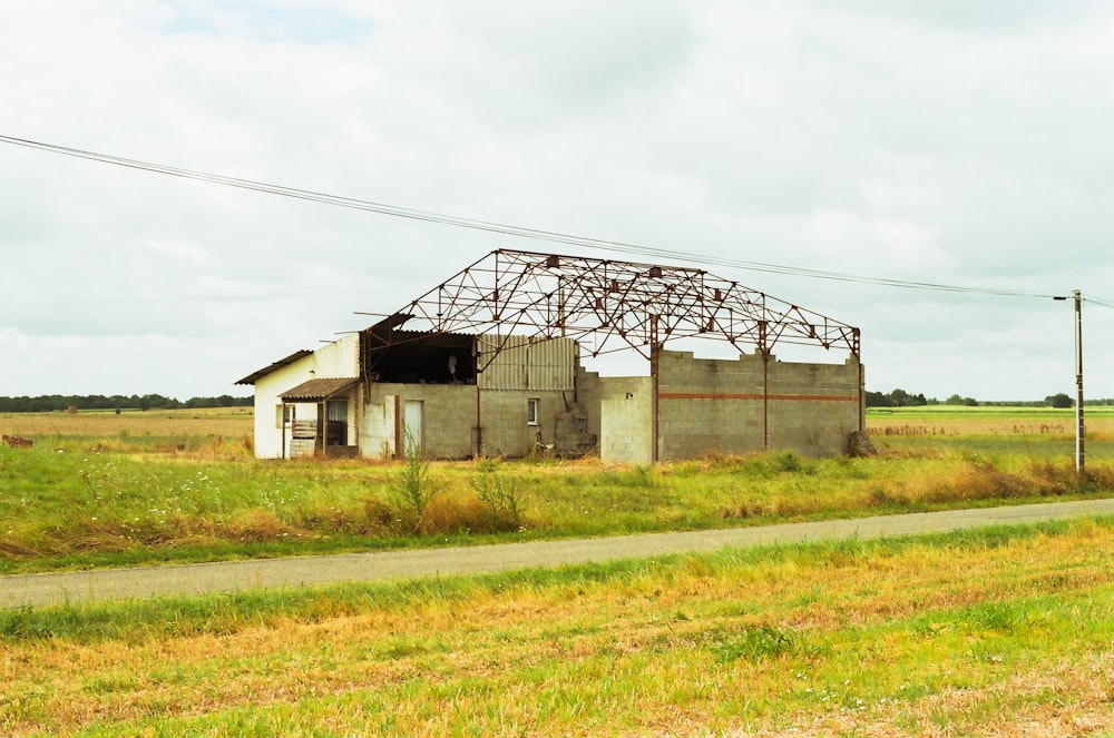 a run down building sitting in a field next to a road