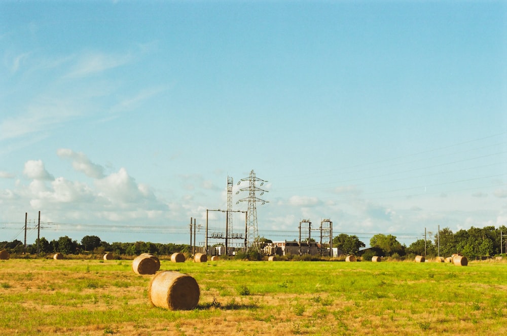 a field with hay bales in the foreground and power lines in the background