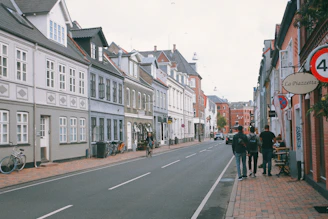 a group of people walking down a street next to tall buildings