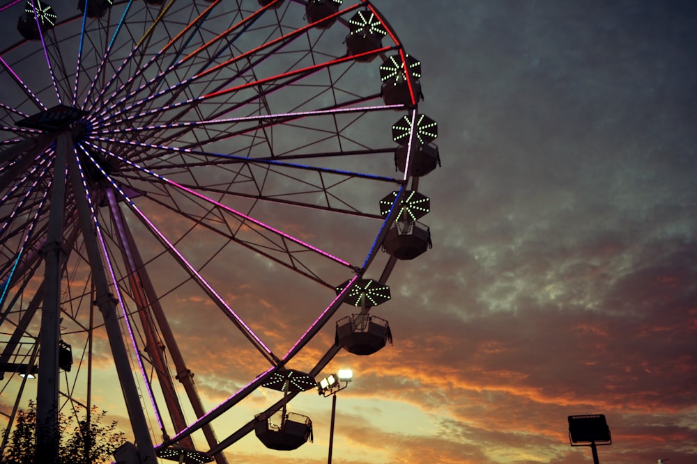 a ferris wheel is lit up at sunset